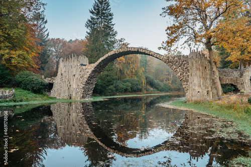 Unique looking bridge Rakotzbrucke,also called Devils Bridge,Saxony,Germany.Built to create circle when it is reflected in waters.Colorful fall landscape.Fantastic autumn foliage.Amazing place © Eva