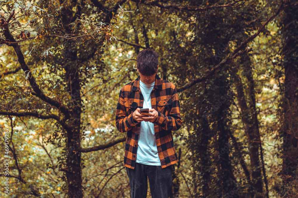teenager looking at mobile phone outdoors with autumn styling teenager looking at mobile phone outdoors with autumn styling