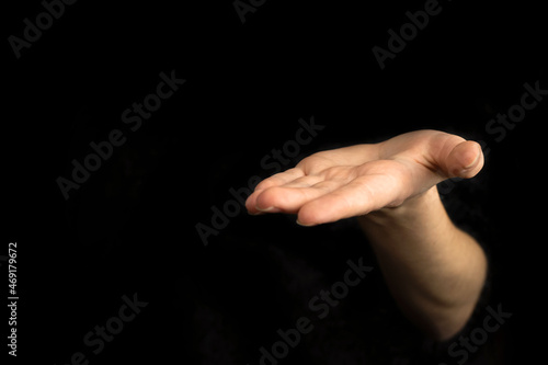 Giving hand gesture, empty woman hand on a black background