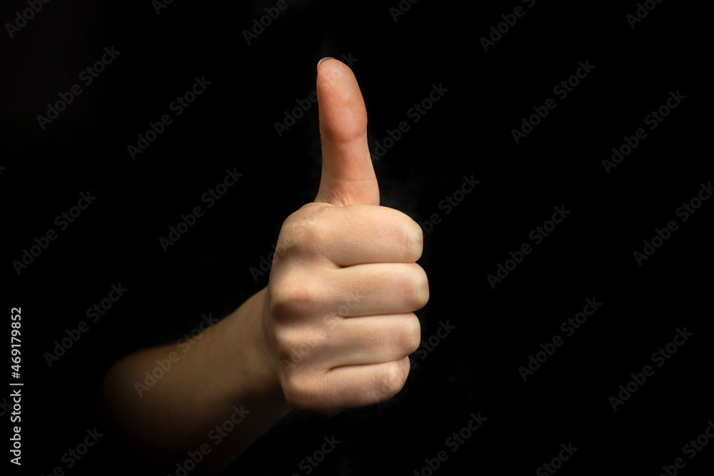 Success gesture, hand with thumb up sign on a black background, business concept photo