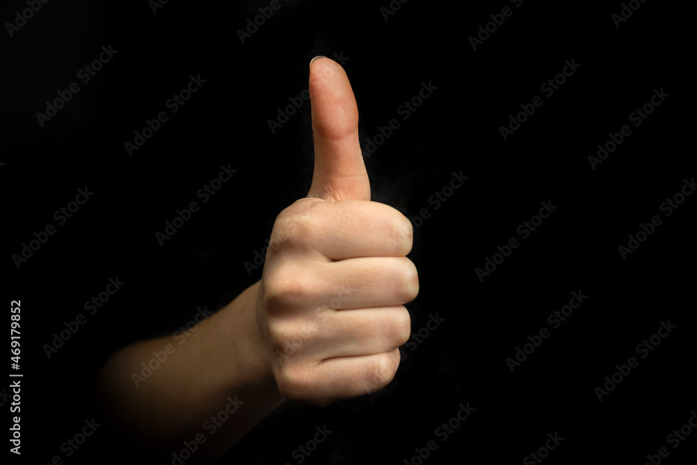 Success gesture, hand with thumb up sign on a black background, business concept photo Success gesture, hand with thumb up sign on a black background, business concept photo