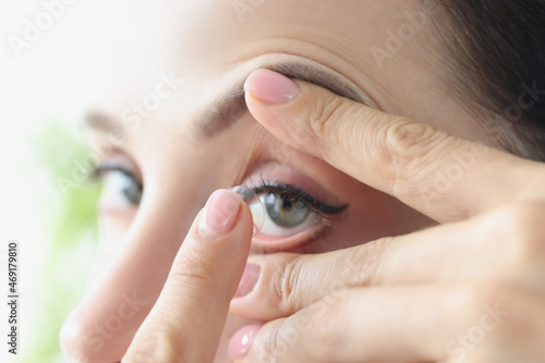 Woman puts on long-term soft contact lenses closeup