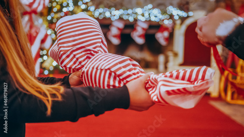 Close up of female hands making a big Christmas decoration in the form of candy in a Christmas store or house. In the background, the fireplace is decorated with Christmas lights and socks.