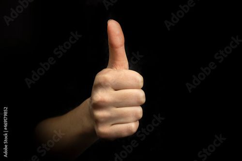 Success gesture, hand with thumb up sign on a black background, business concept photo