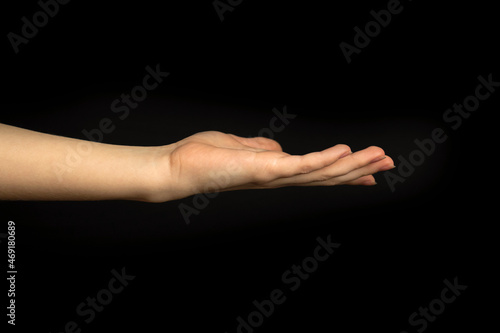 Empty hand gesture on a black background. Woman hand with palm up
