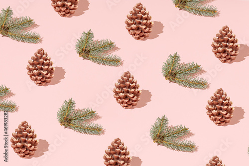 Trendy Christmas pattern with green fir branches and cones on pastel pink background. Minimal New year holiday wallpaper