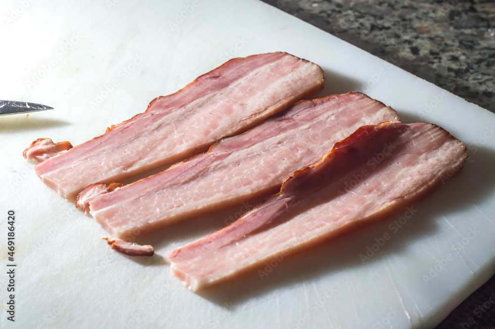 bacon sliced ​​on a white board with copy space to the left and selective focus
