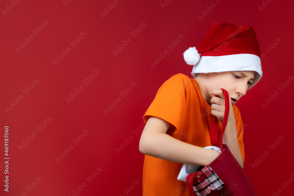 Fototapeta premium a boy with a Christmas bag rummages in search of gifts