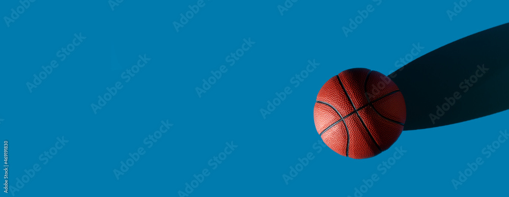 Brown new basketball ball with natural lighting on blue background. Sport team concept. Horizontal sport theme poster, greeting cards, headers, website and app