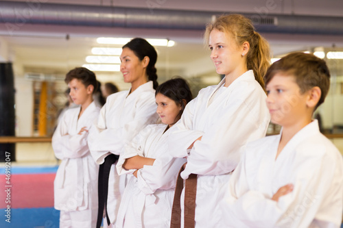 Group photo of kids and trainer in karate uniform standing in gym. © JackF