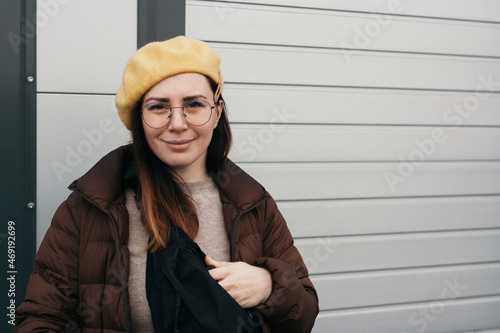 Portrait of woman in warm clothing and glasses on grey background