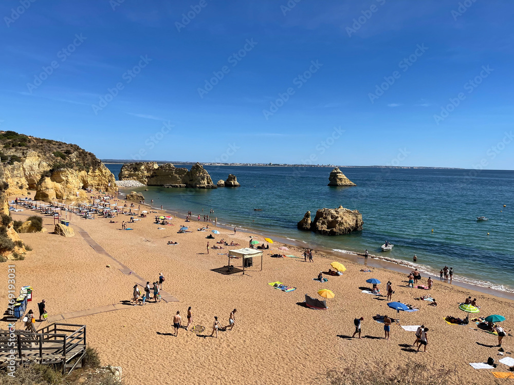 Obraz premium Praia Dona Ana beach with turquoise sea water and cliffs, flying seagulls over the beach, Portugal. Beautiful Dona Ana Beach (Praia Dona Ana) in Lagos, Algarve, Portugal..