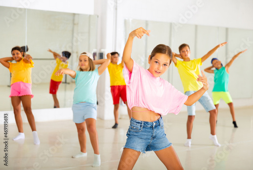 Portrait of modern tween girl krump dancer in choreographic studio with dancing children in background.