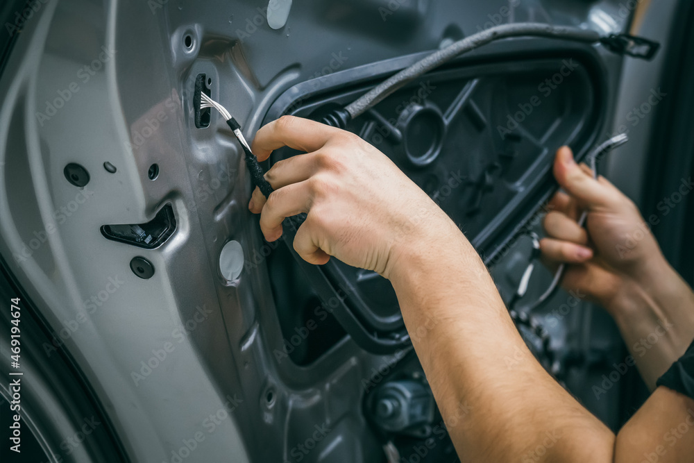Auto service worker disassembles car door for repair, restoration, tuning car sound or installing noise insulation or soundproofing. Auto service worker disassembles car door for repair, restoration, tuning car sound or installing noise insulation or soundproofing.