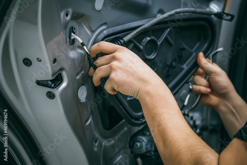 Auto service worker disassembles car door for repair, restoration, tuning car sound or installing noise insulation or soundproofing. photo