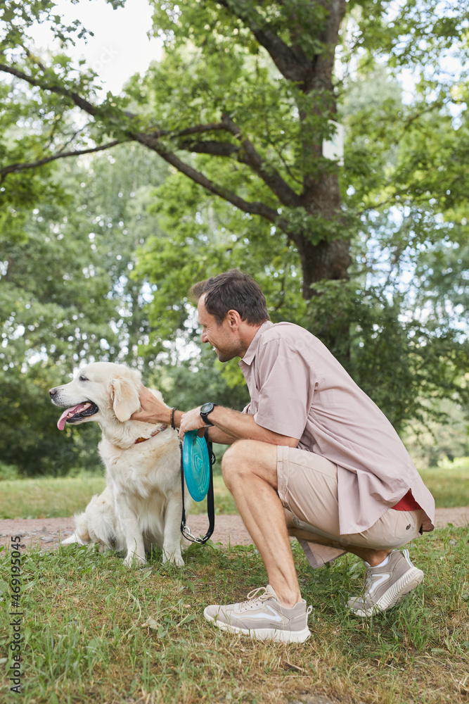 Vertical side view portrait of happy man playing with dog outdoors in Summer at green park Vertical side view portrait of happy man playing with dog outdoors in Summer at green park