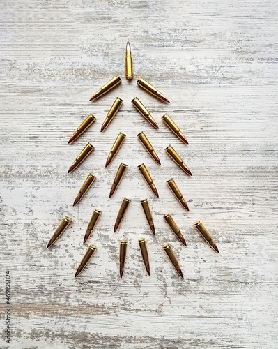 Postcard with an unusual Christmas tree in military style made of cartridges for AK 47. Concept Military tree made of cartridges on a white wooden background. Flatley from cartridges for the New Year.