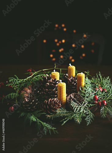 Hand crafted rustic Christmas wreath with beeswax candles, cones and evergreen sprigs . Copy space