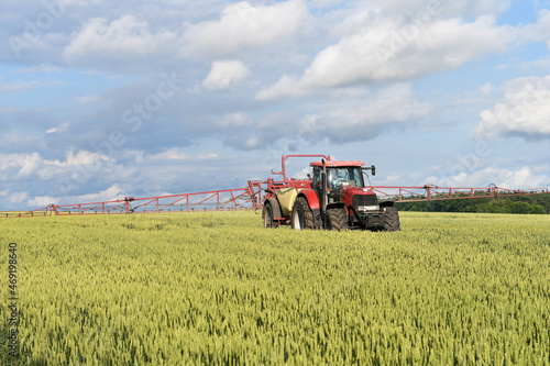 Agricultural machinery working in wheat  field  spreading fertilizers at springtime. 