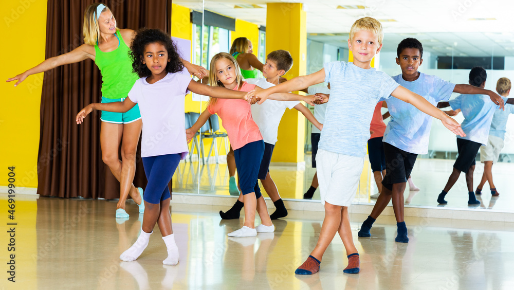 Tweenagers in pairs learning to dance active boogie-woogie with female teacher in modern studio