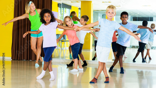 Tweenagers in pairs learning to dance active boogie-woogie with female teacher in modern studio