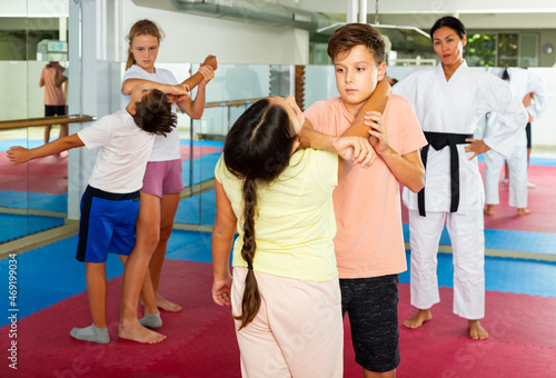 Teenage boys and girls in pairs practicing self-protection during group class at gym