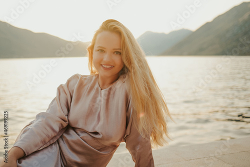 Portrait of a beautiful young blonde against a background of mountains and the sea, beautiful nature. Travel at sunset