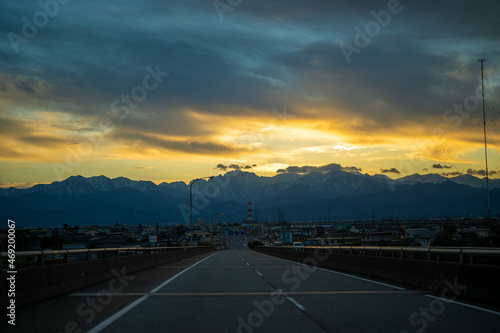 富山県富山市の道路から朝焼けの剱岳や立山を見る風景 View of Tsurugidake and Tateyama in the morning sun from the road in Toyama City, Toyama Prefecture, Japan.