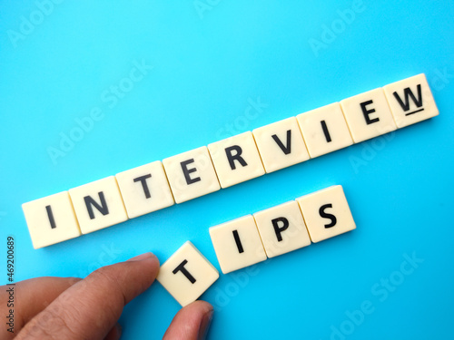 Hand holding toys word with text INTERVIEW TIPS on blue background.