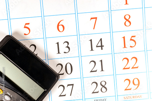 Planning monthly budget and expenses. Black calculator is on the paper calendar. 