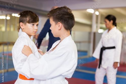 Pair of teenager boys wearing kimono practicing new karate moves during training in gym