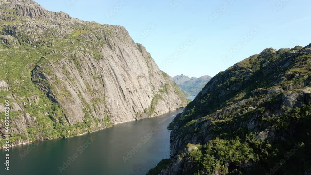 Aerial view of a boat between steep mountain narrows, in Norway - tracking, drone shot Aerial view of a boat between steep mountain narrows, in Norway - tracking, drone shot