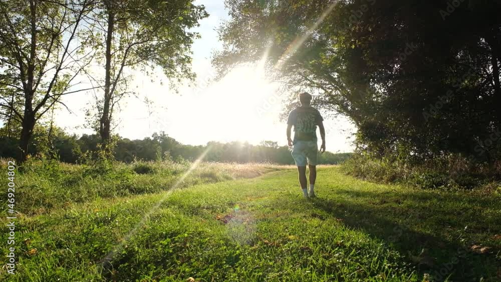 shot of a man walking away from the camera on a trail next to Maremeck River in Missouri. shot of a man walking away from the camera on a trail next to Maremeck River in Missouri.