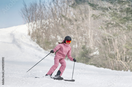 Skiing - Woman on ski. Alpine ski concept - skier skiing downhill at mountain snow covered ski trail slopes in winter on perfect powder snow enjoying nature landscape. Elegant pink ski clothing