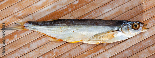 One dried salted sabrefish on light wooden background photo