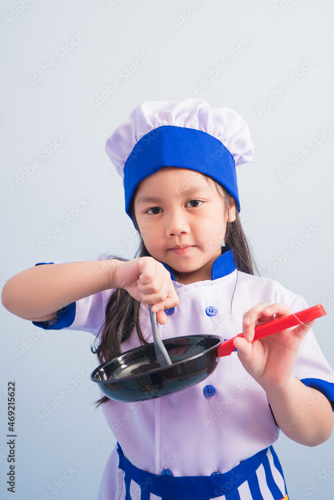 Happy girls with amazing smile in clothes and chef cap. child dreams of becoming a chef Happy girls with amazing smile in clothes and chef cap. child dreams of becoming a chef
