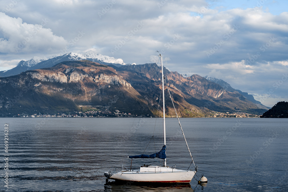 Yacht with a folded sail against a background of mountains. Lake Como, Italy