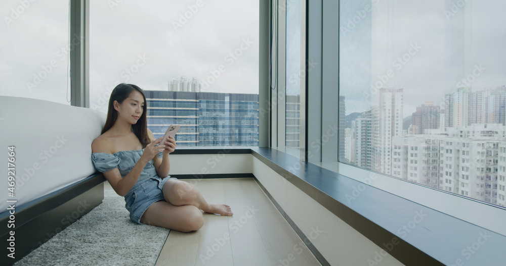 Woman use of mobile phone and sit beside the bed Woman use of mobile phone and sit beside the bed