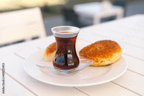 Photography Crispy Turkish traditional bagel, simit with sesame and glass of turkish black tea, turkish breakfast pastry concept