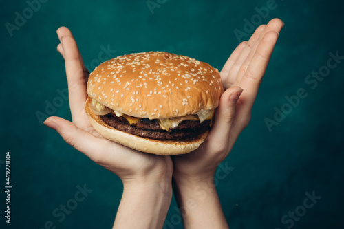 hamburger in hands close-up fast food green background