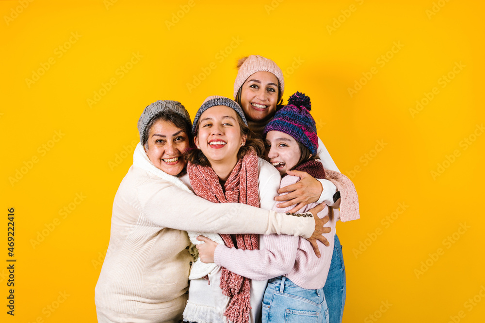 Winter portrait of happy latin family three generations of hispanic women on yellow background in Mexico Latin America
