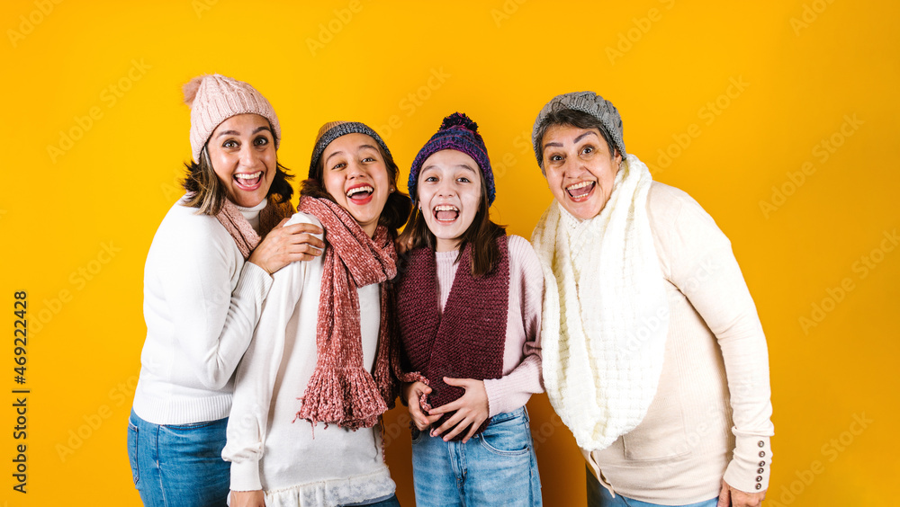 Winter portrait of happy latin family three generations of hispanic women on yellow background in Mexico Latin America
