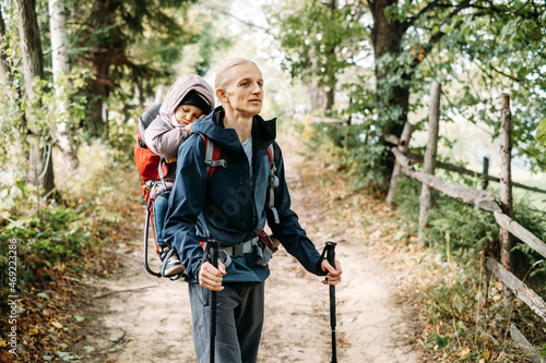 Sleepy tired child walking with father in backpack in the mountains. Nordic walk with family and kid in fall. obstacles and challenges for man traveling outdoors. Adventure hiking tour  © ninelutsk