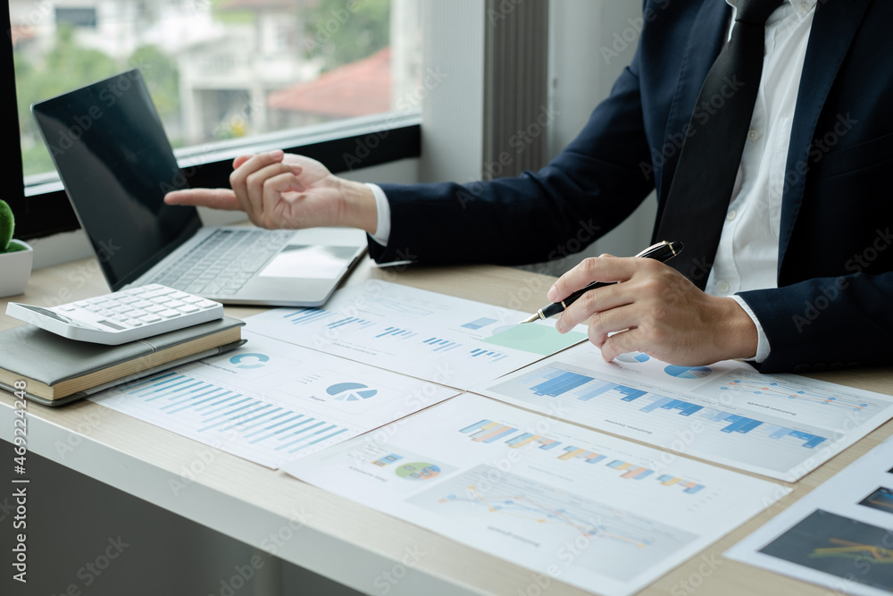 The hand of businessman sit at their desks and calculate financial graphs showing results about their investments, plan a successful business growth process The hand of businessman sit at their desks and calculate financial graphs showing results about their investments, plan a successful business growth process
