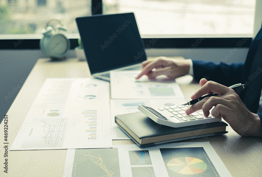 The hand of businessman sit at their desks and calculate financial graphs showing results about their investments, plan a successful business growth process The hand of businessman sit at their desks and calculate financial graphs showing results about their investments, plan a successful business growth process