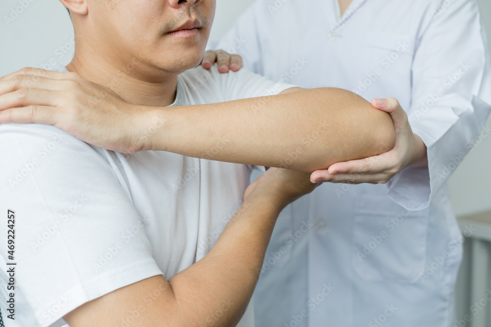 Obraz premium Female physiotherapists provide assistance to male patients with elbow injuries examine patients in rehabilitation centers. Physiotherapy concepts