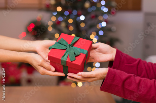 Happy woman giving Christmas and New Year Gift box to woman at Home. Family Xmas celebration. Person Holding, Receiving a Gift box.
