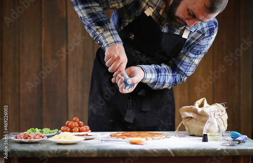 man preparing a pizza, knead the dough and puts ingredients