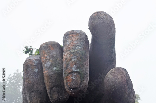 Sculpture of a giant hand, various plants grow on the back of the palm, the index finger points to the viewer