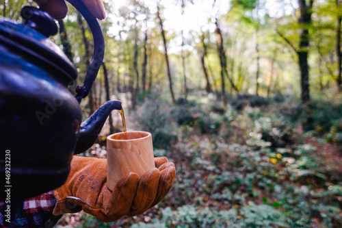 A man holds a traditional wooden Kuksa mug. Autumn forest, close-up. © sercansamanci